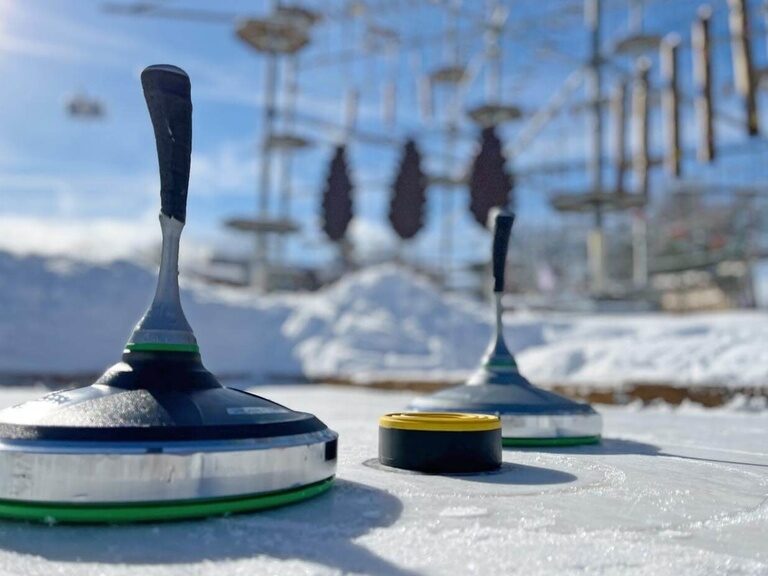 Nahaufnahme zweier Eisstöcke im Schnee, dahinter erkennt man den Kletterturm.