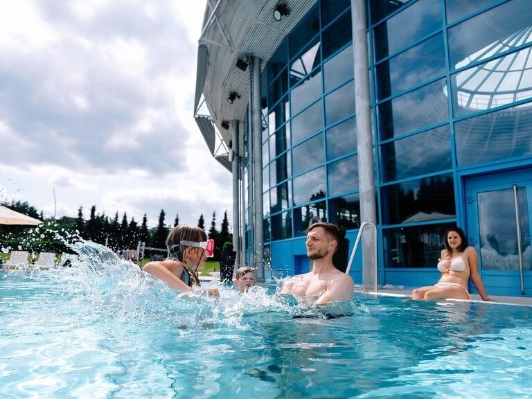 Eine Familie plantscht vernügt im beheizten Außenbecken.