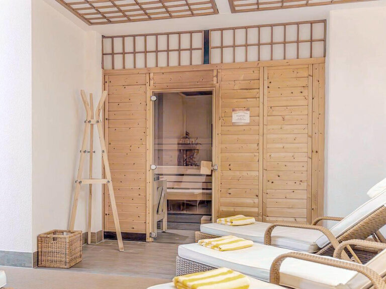 Ruheraum mit Blick über Relax-Liegen zur holzverkleideten Dampfsauna.