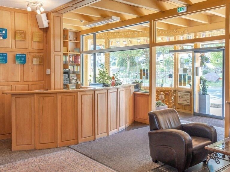 Die mit Holz verkleidete Rezeption des Hotels wirkt durch ihre großen Fensterfronten sehr hell und einladend.