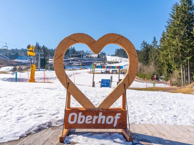 Blick durch ein reisiges Herz aus Holz auf den Alpinski-Hang von Oberhof.