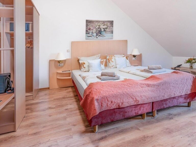 Blick ins Komfortzimmer mit großem Doppelbett in gemütlichen Naturtönen.