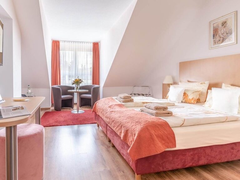 Komfortzimmer mit Schreibtisch, Sitzecke und großem Doppelbett.