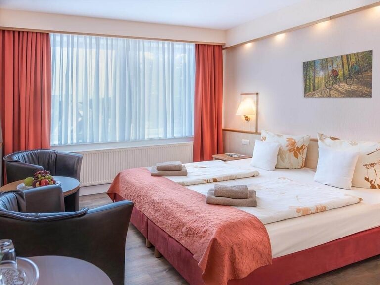 Standardzimmer in behaglichen Erd- und Rottönen mit Hartboden