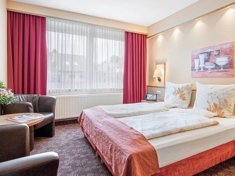 Standardzimmer in gemütlichen Erdtönen und Rottönen mit Teppichboden