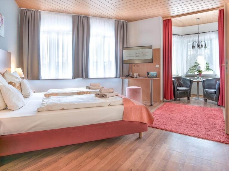 Gemütliches Zimmer mit Sitznische, in der zwei Cocktailsessel stehen.