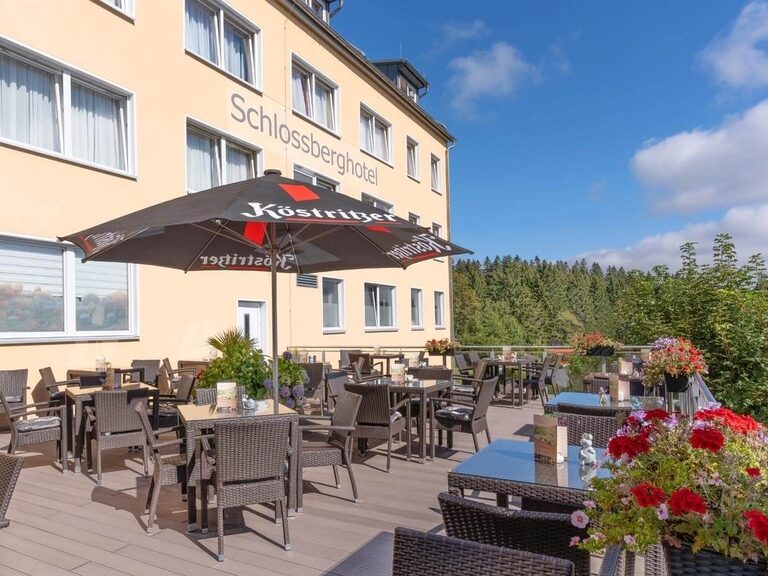 Terrasses des Hotels an eine sonnigen Tag mit geöffnetem Sonnenschirm.