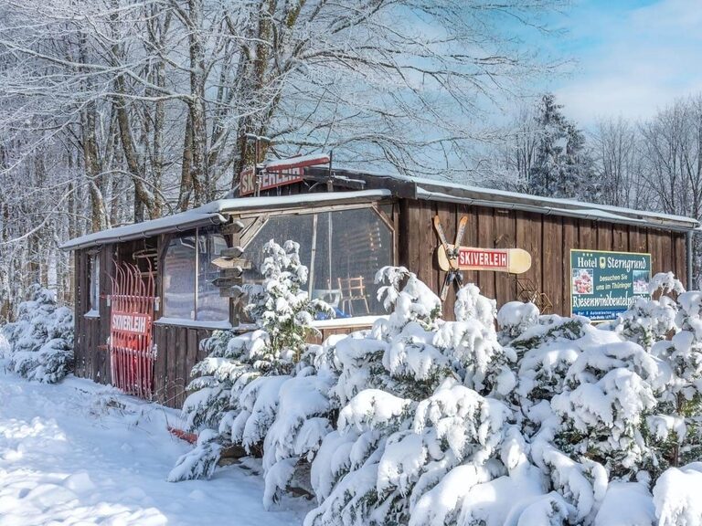 Holzhütte am Parkplatz nahe des Rodelhangs, deokiert mit Skiern.