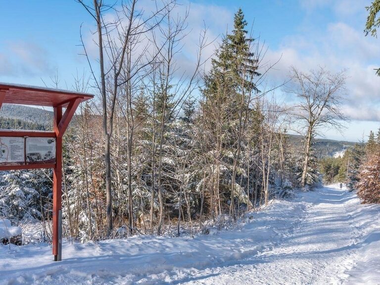 Historischer Sportstättenwanderweg in winterlichem Weiß und Schautafel am Wegesrand.